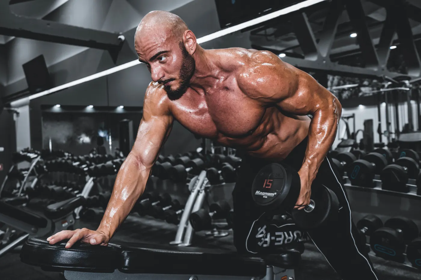 Man performing a controlled dumbbell exercise in a gym