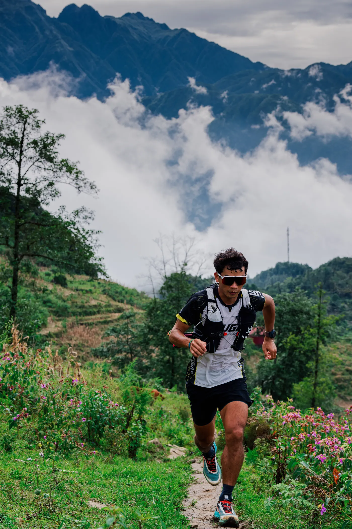 Trail runner crossing a rugged mountain path under cloudy skies