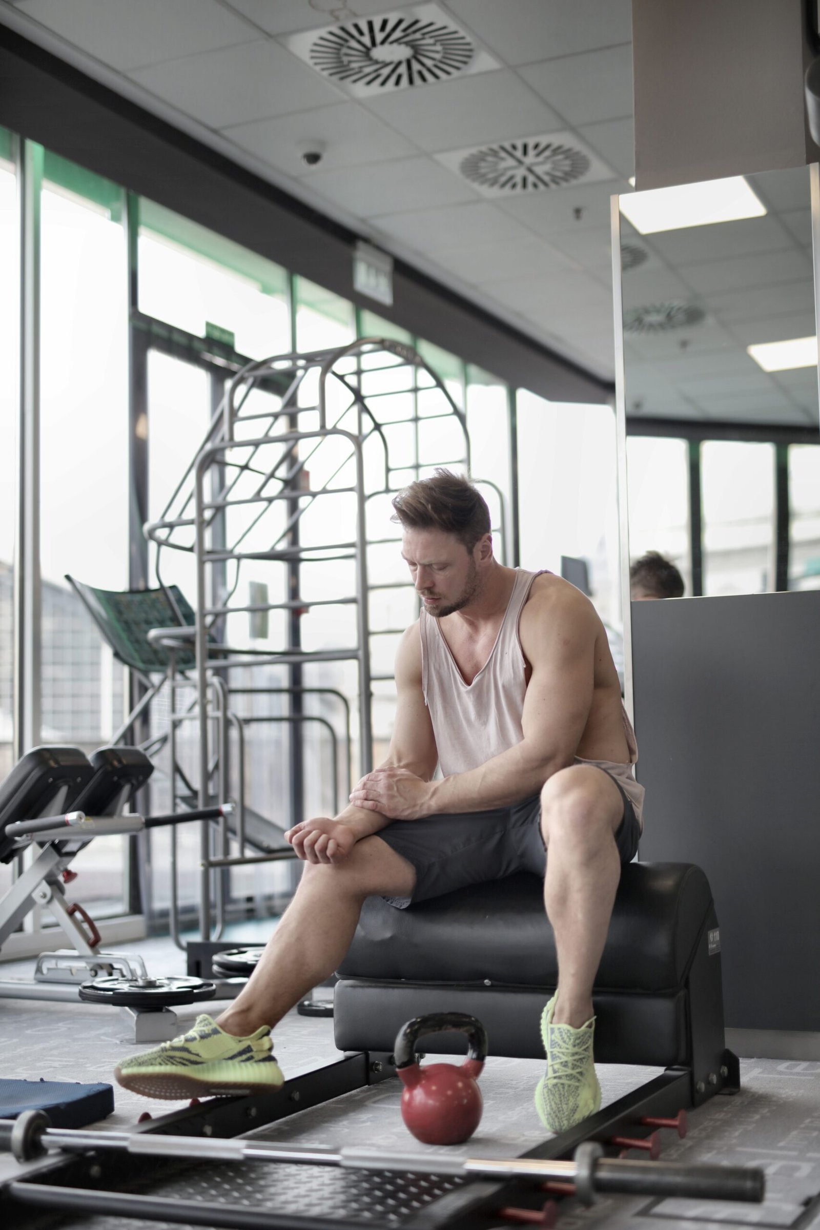 Lifter taking a recovery break beside weights in a gym