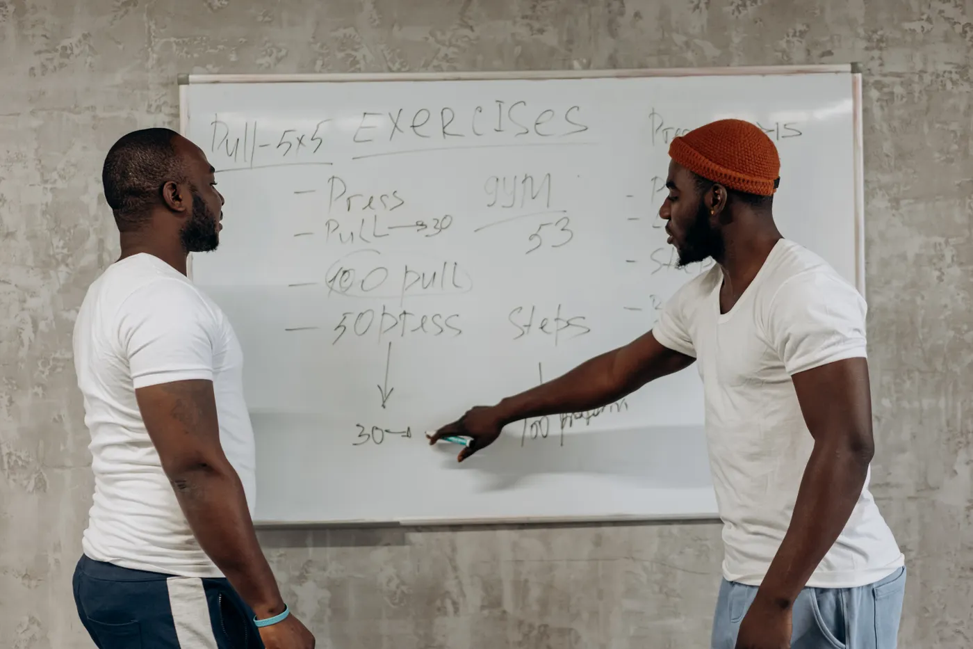 Athletes discussing a workout plan on a gym whiteboard