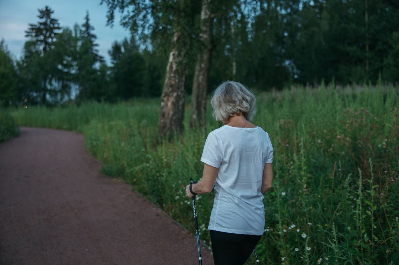 Older woman Nordic walking outdoors in a park
