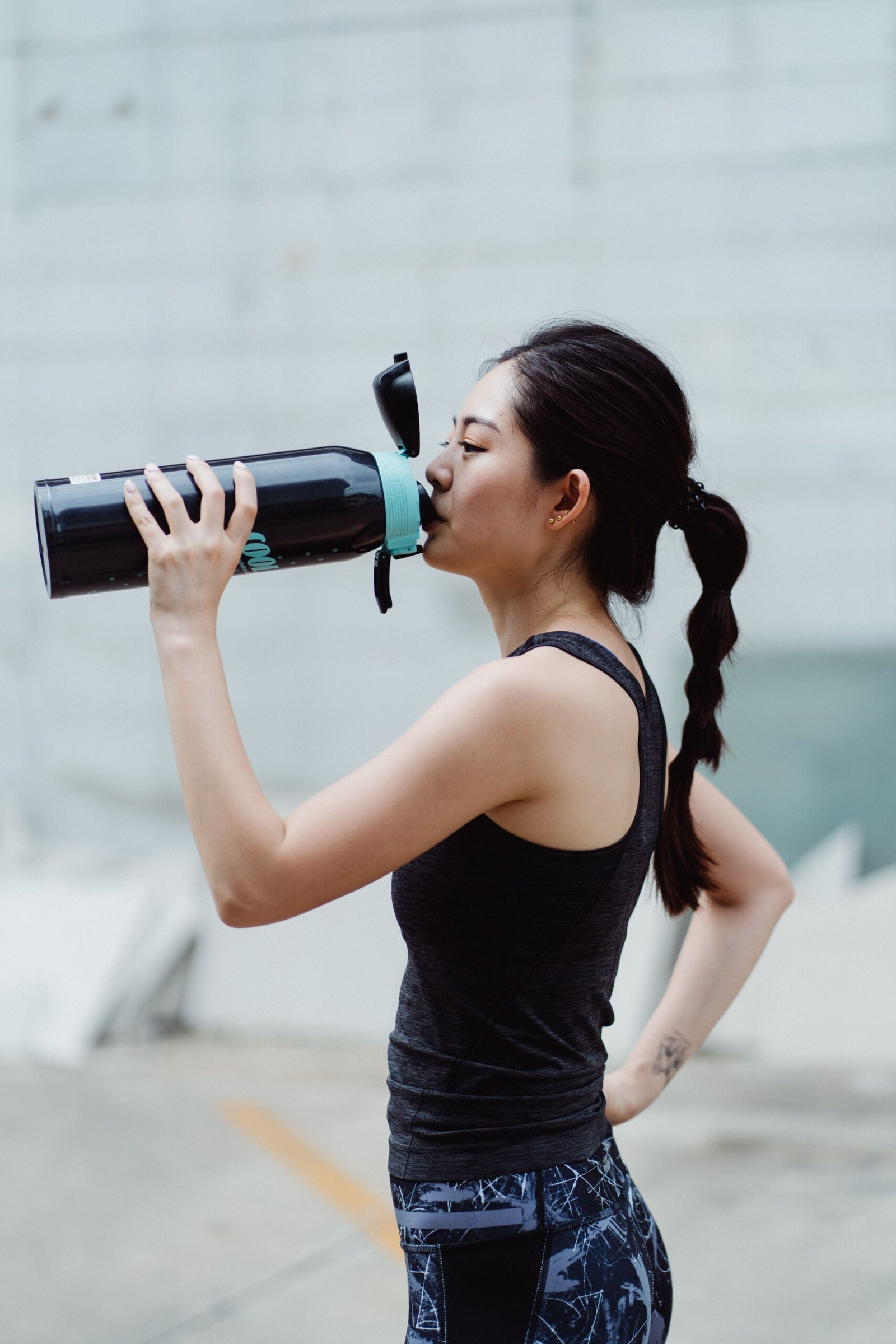 Woman drinking water after an outdoor workout to recover between exercise sessions