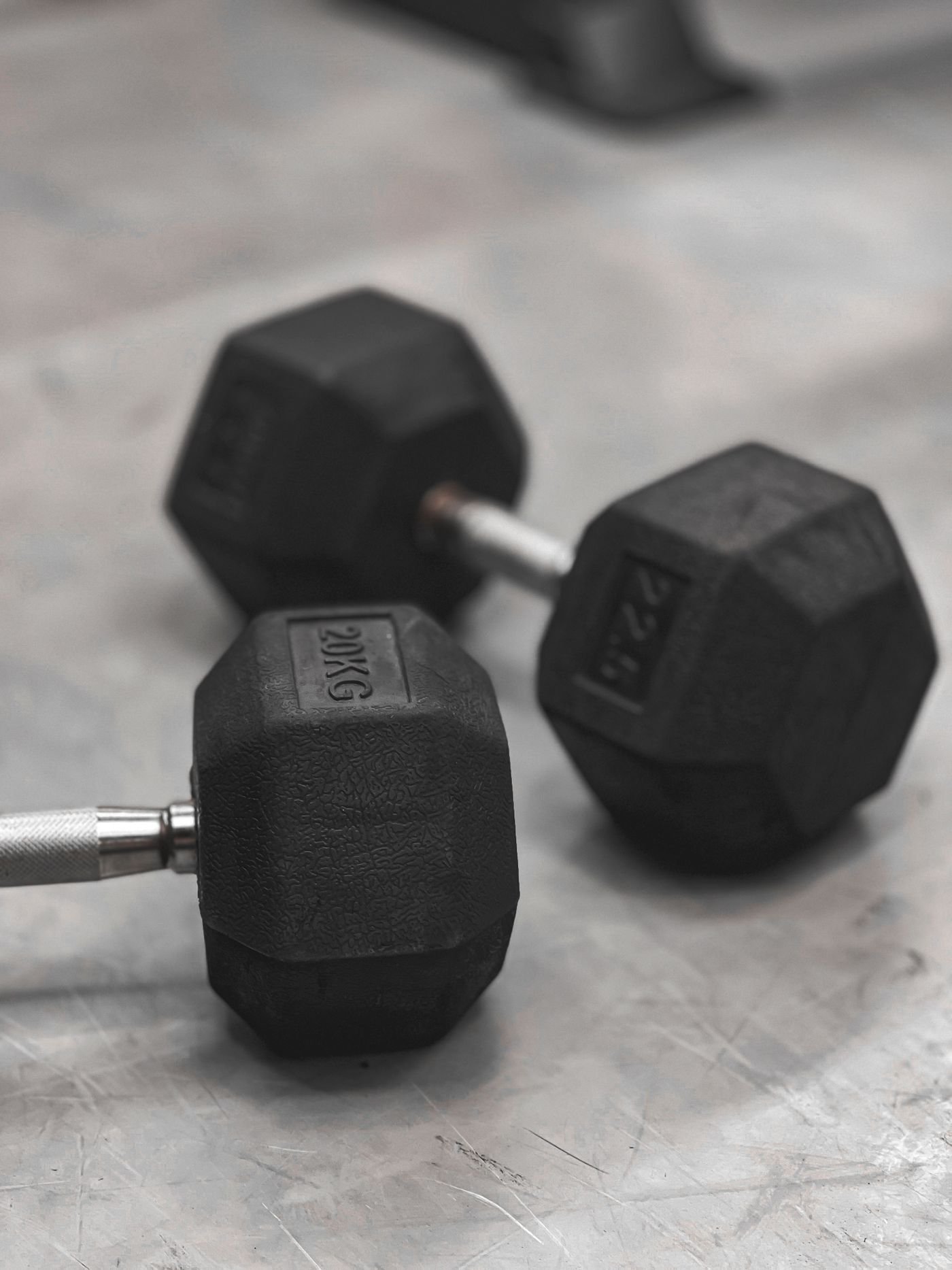 Two hex dumbbells on a gym floor representing simple strength training