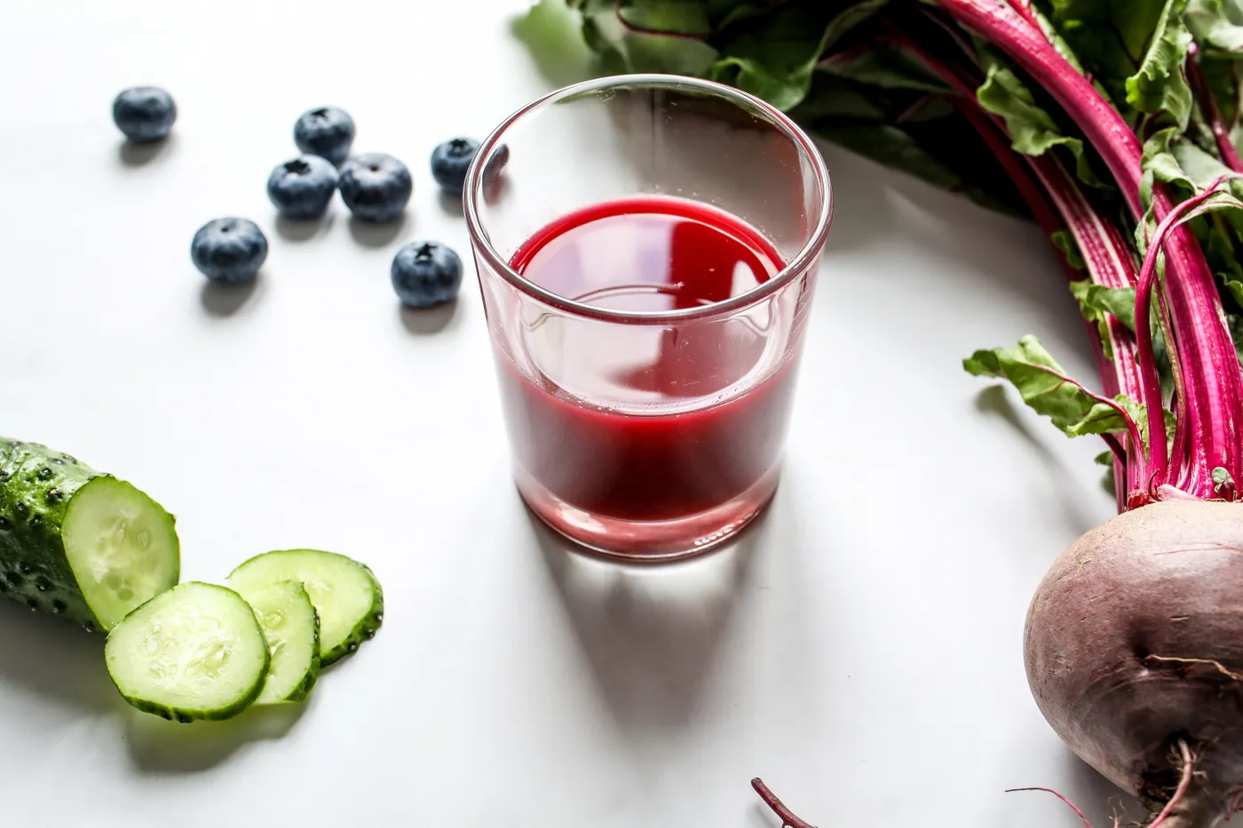 Red beetroot juice beside fresh vegetables