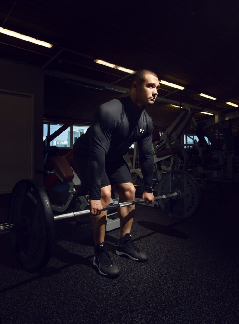 Muscular man lifting a barbell in a dark gym