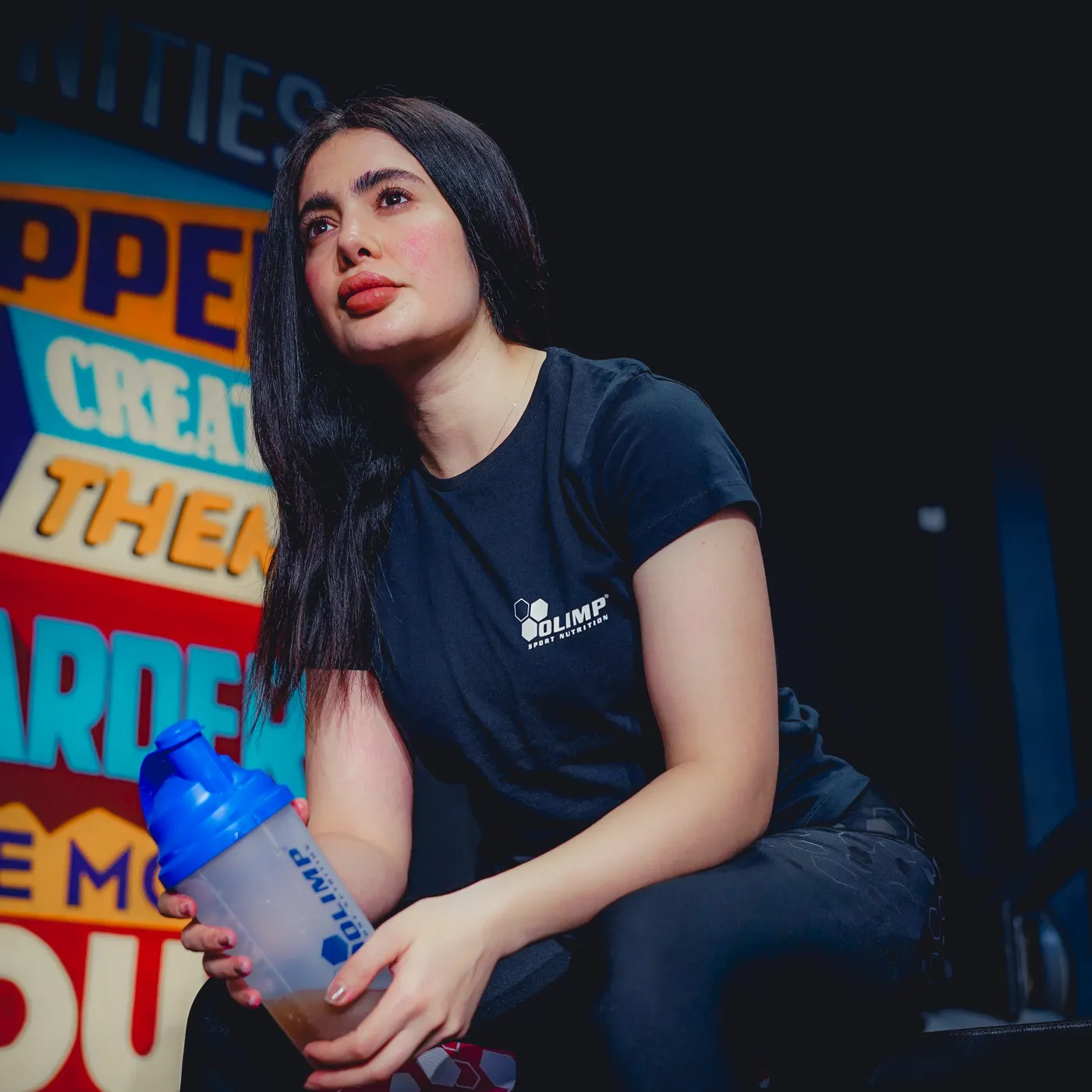 Athlete holding a protein shaker bottle in a gym