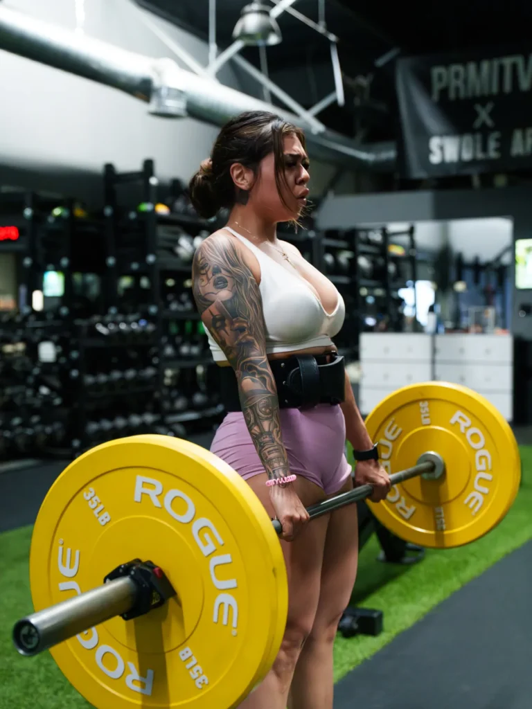 Female athlete performing a barbell deadlift in a gym
