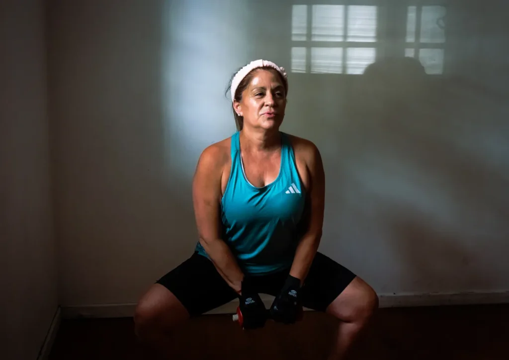 Woman training with dumbbells in a gym, demonstrating a full-body strength session