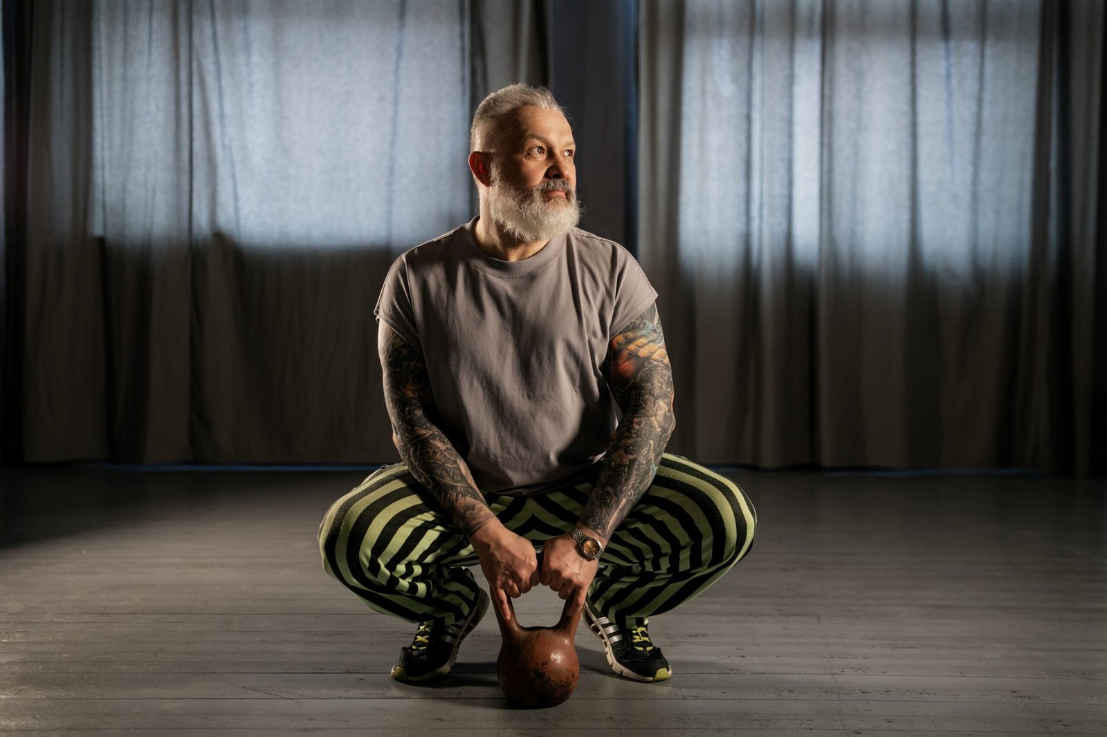 Older man practicing a kettlebell squat indoors