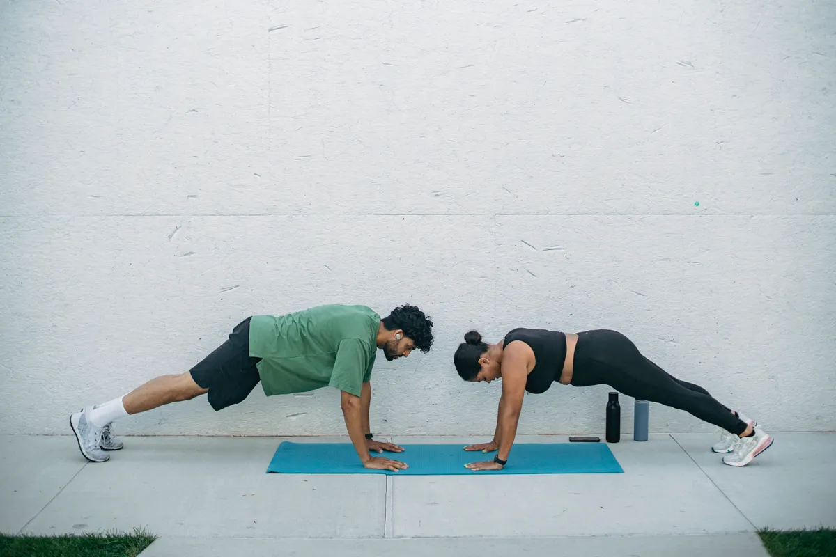Two adults doing plank exercises on exercise mats