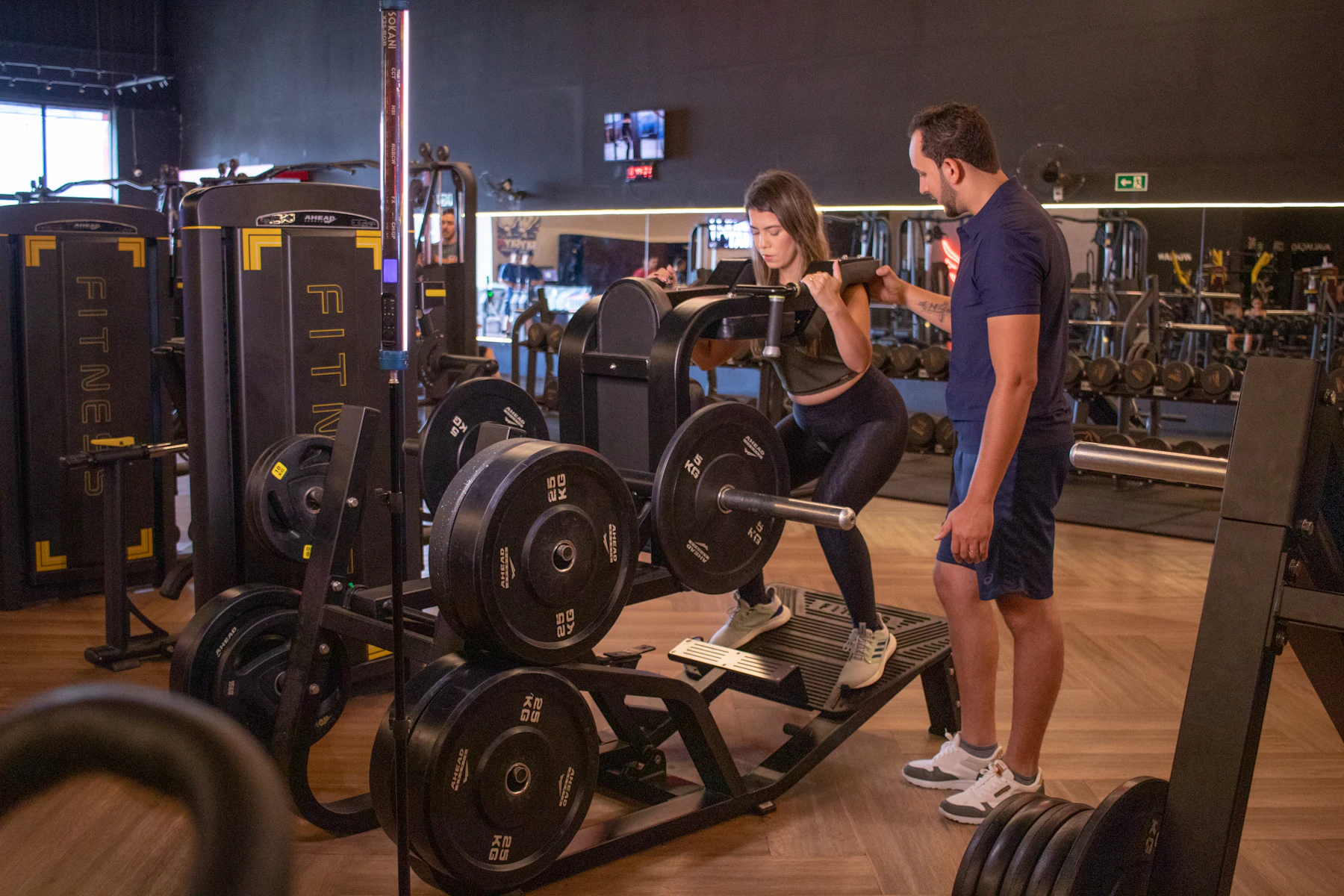 Lifter practicing a squat movement with a trainer nearby