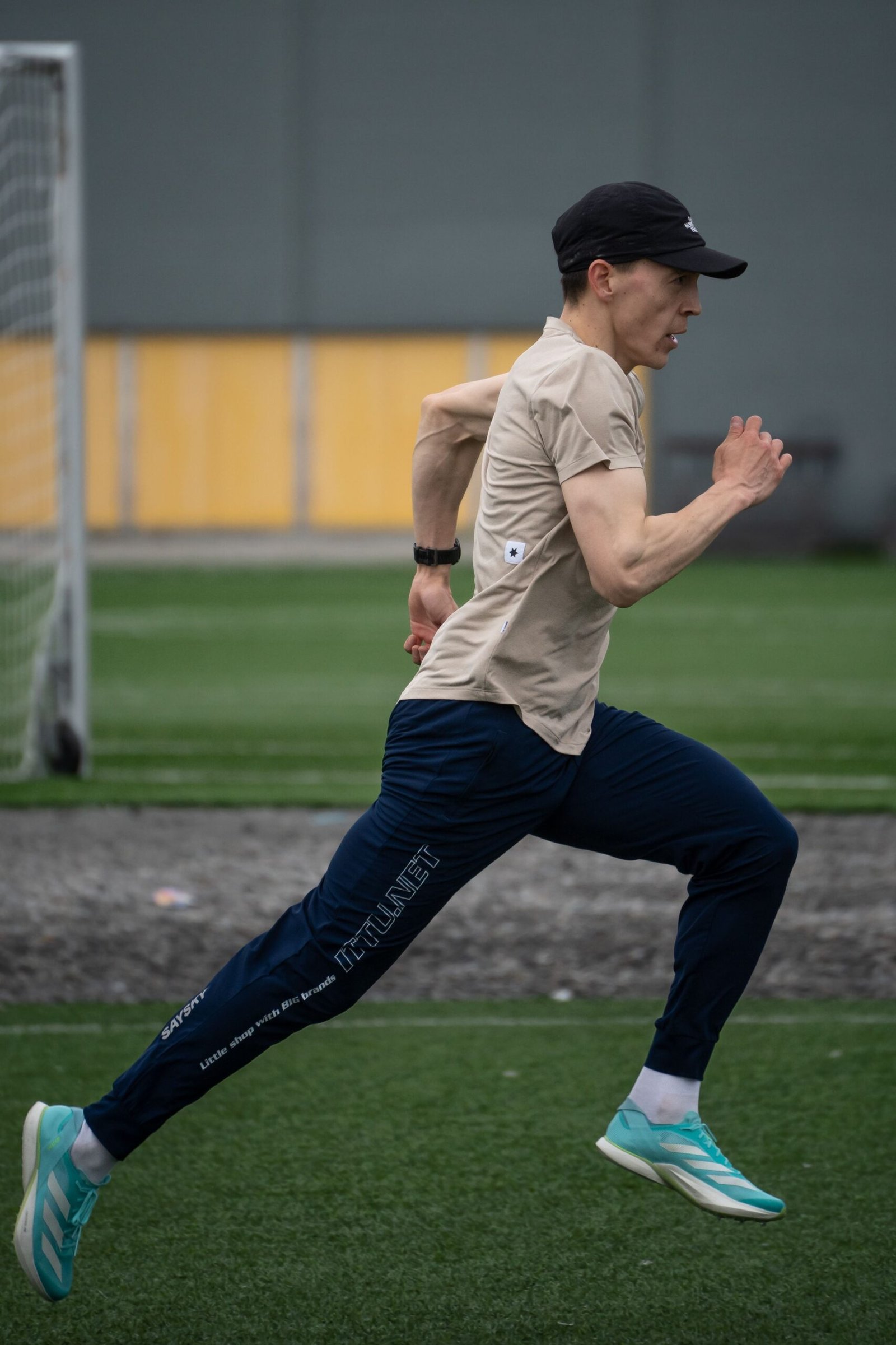 Runner sprinting on a green outdoor football field