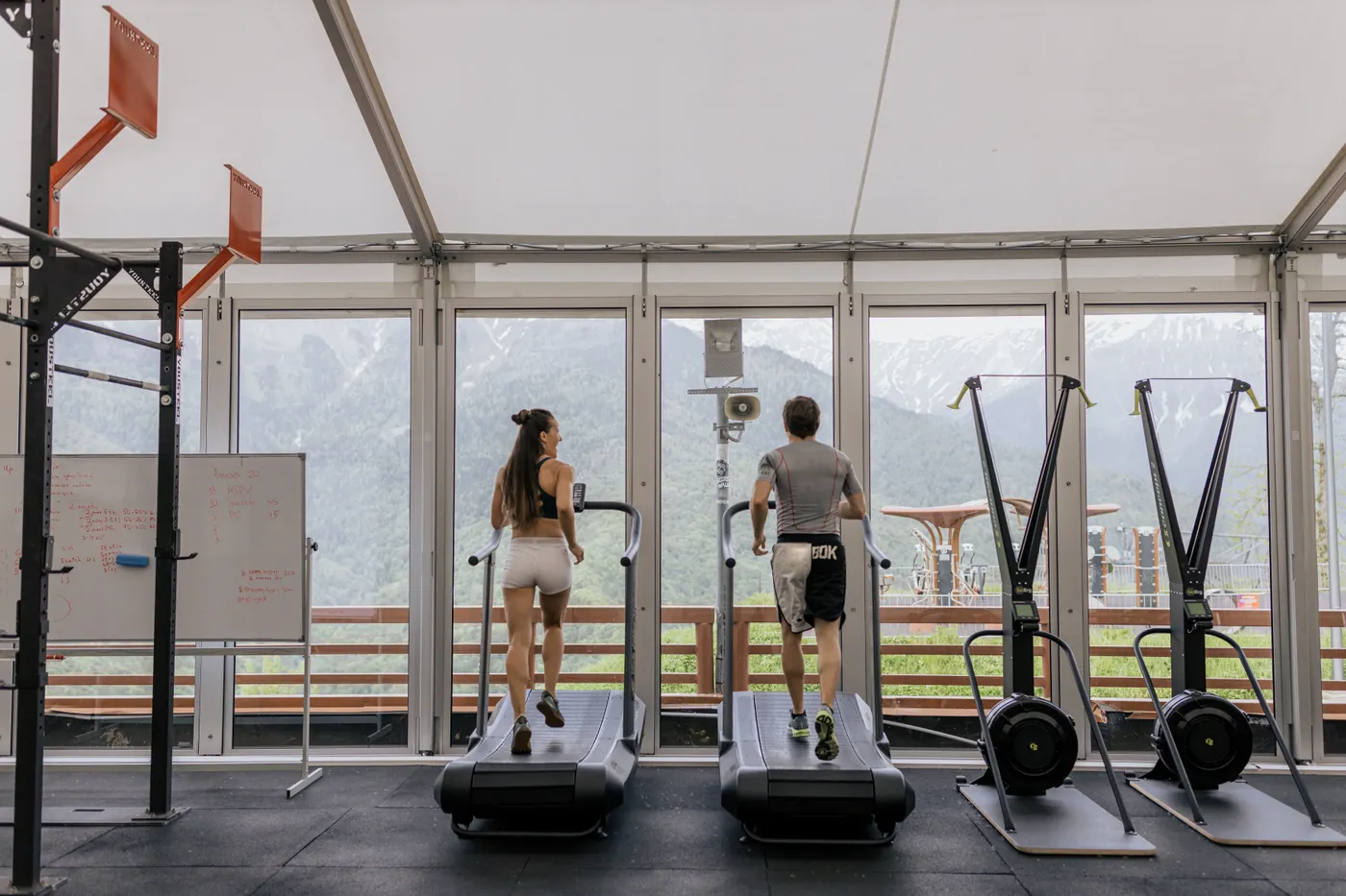 Two athletes running on treadmills in a gym