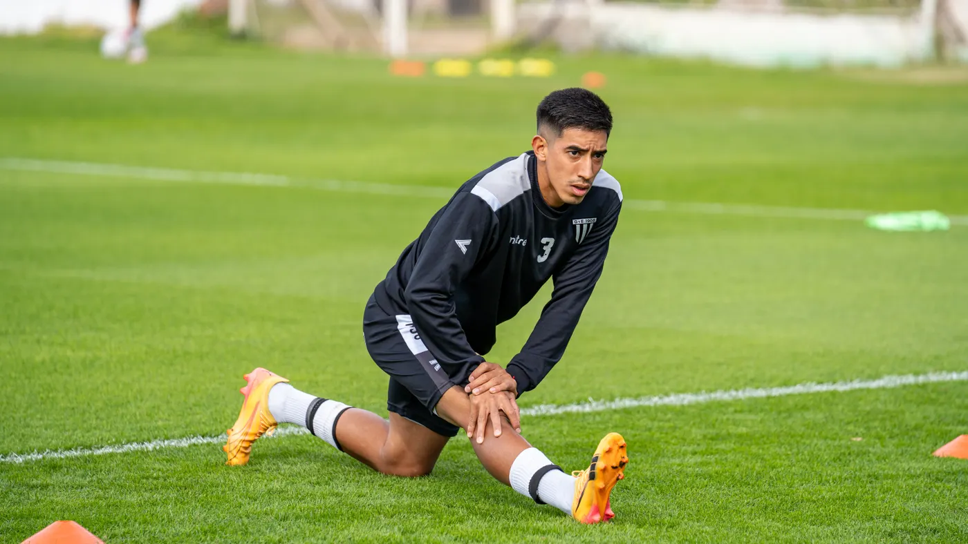 Soccer player stretching on the pitch before practice
