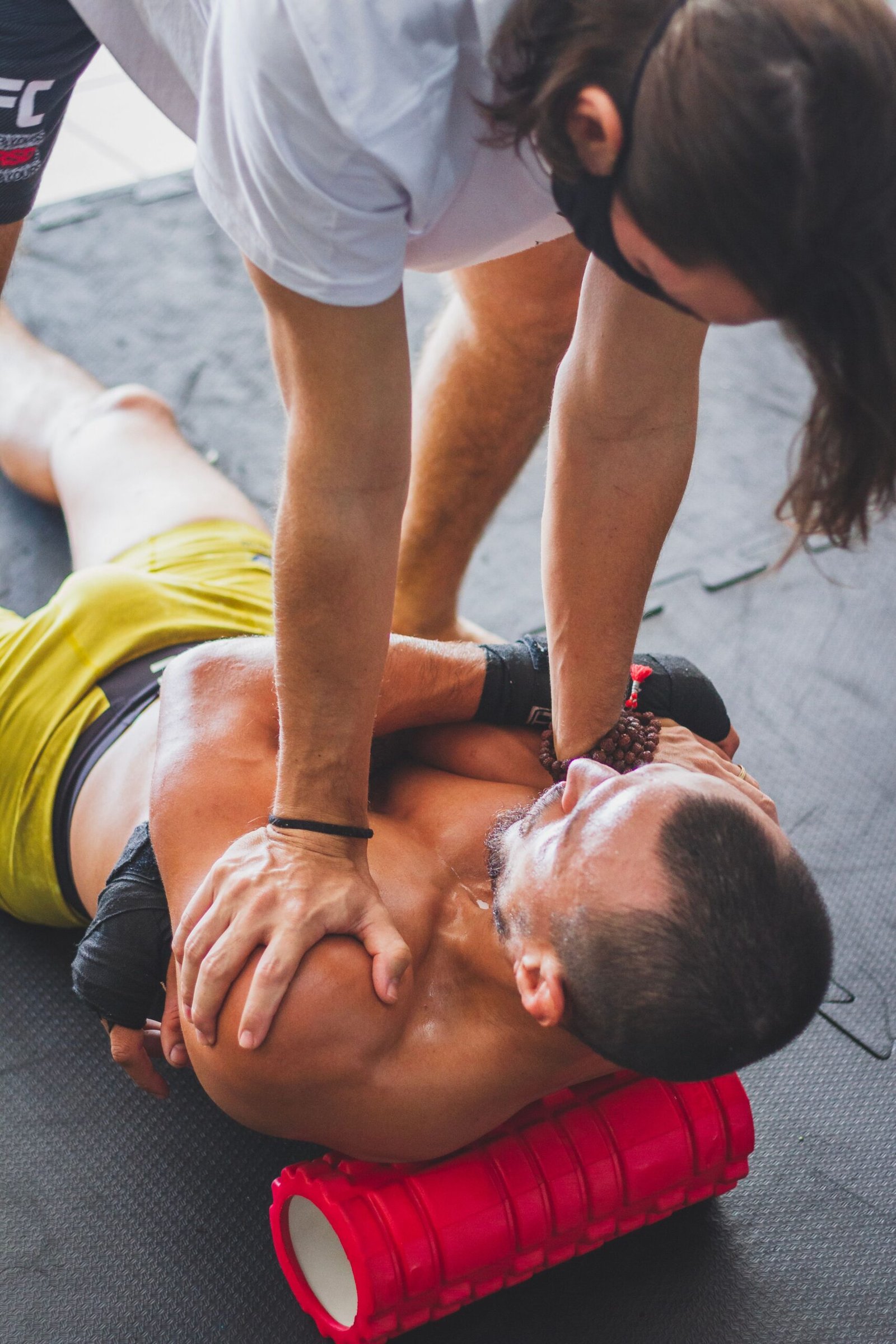 Trainer helping an athlete stretch using a foam roller