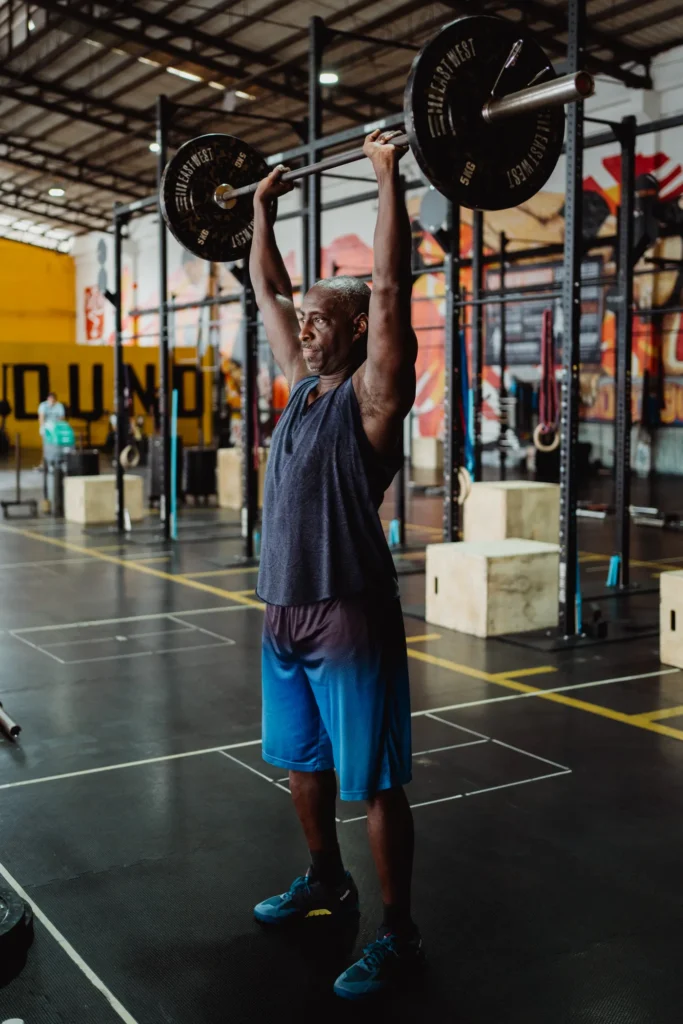 Athlete performing a standing barbell overhead press in a gym
