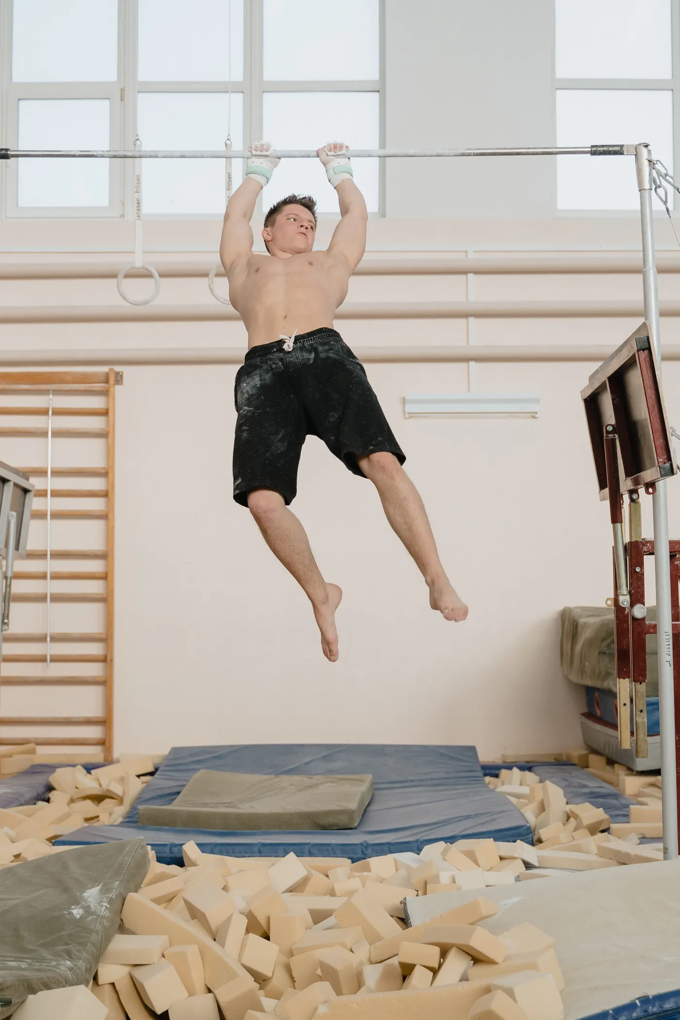 Athlete gripping a pull-up bar inside a gym