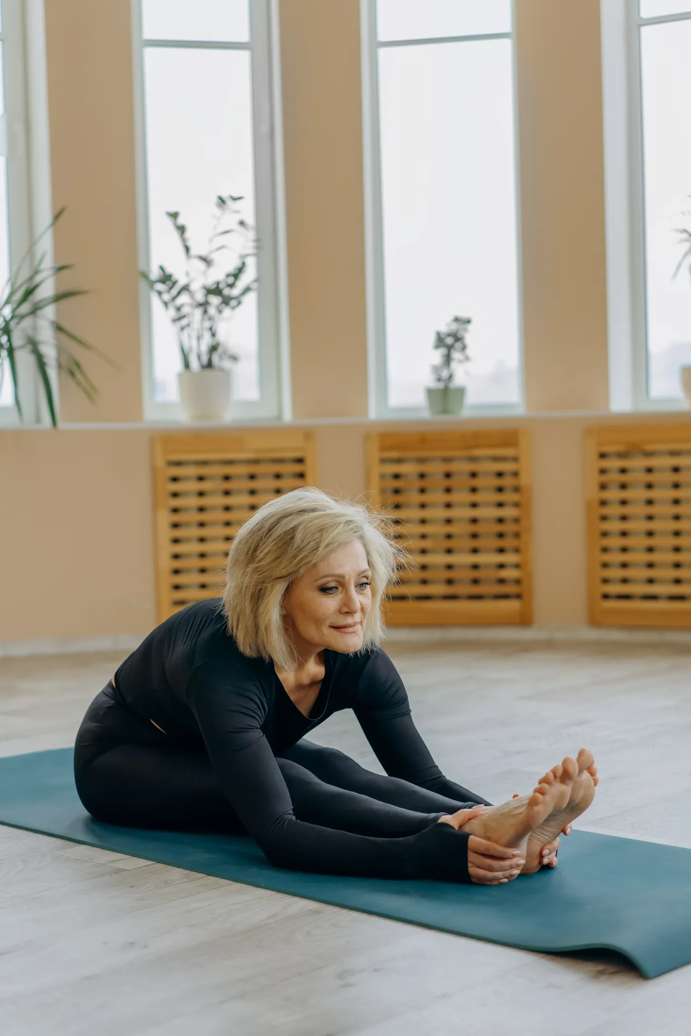 Senior woman stretching on a yoga mat indoors