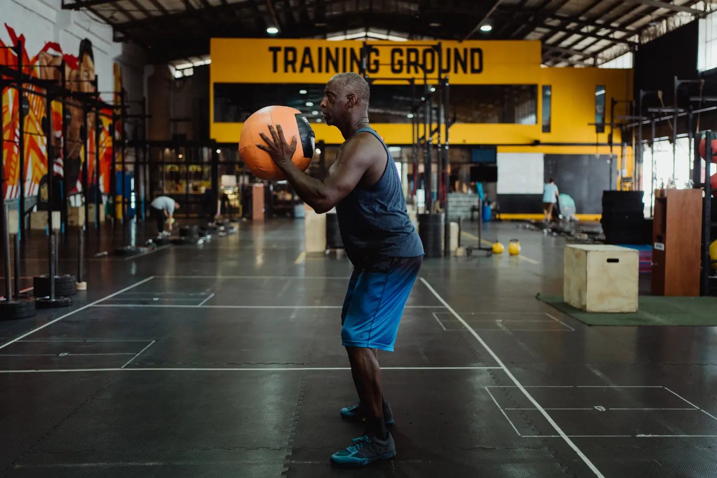 Man preparing a medicine-ball drill on a gym floor