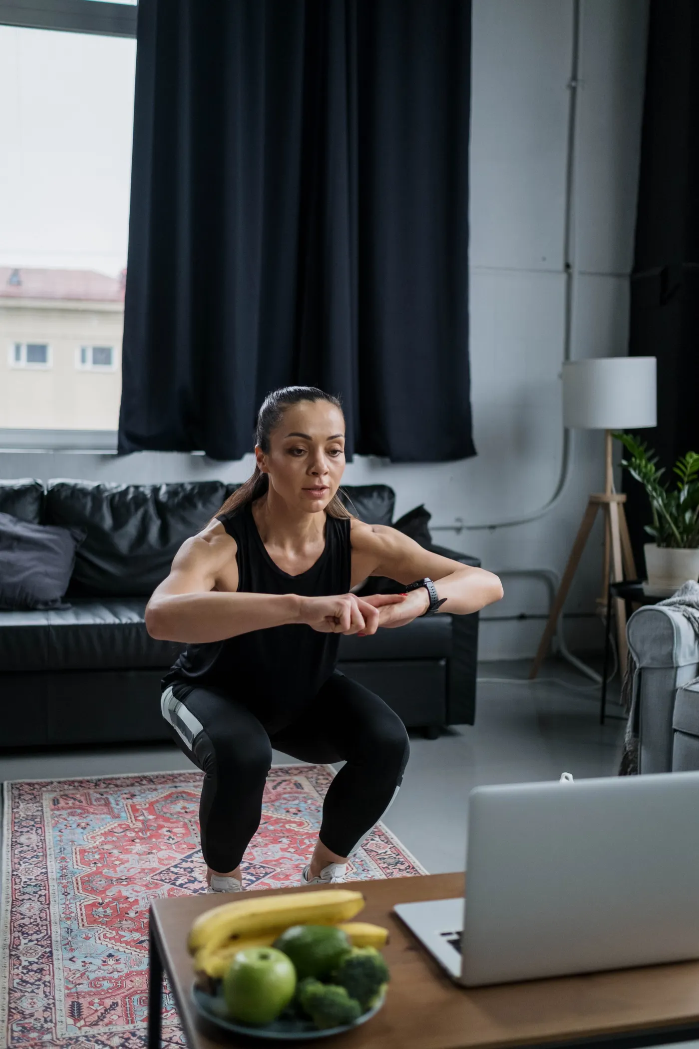 Woman doing squats during an online exercise session in her living room