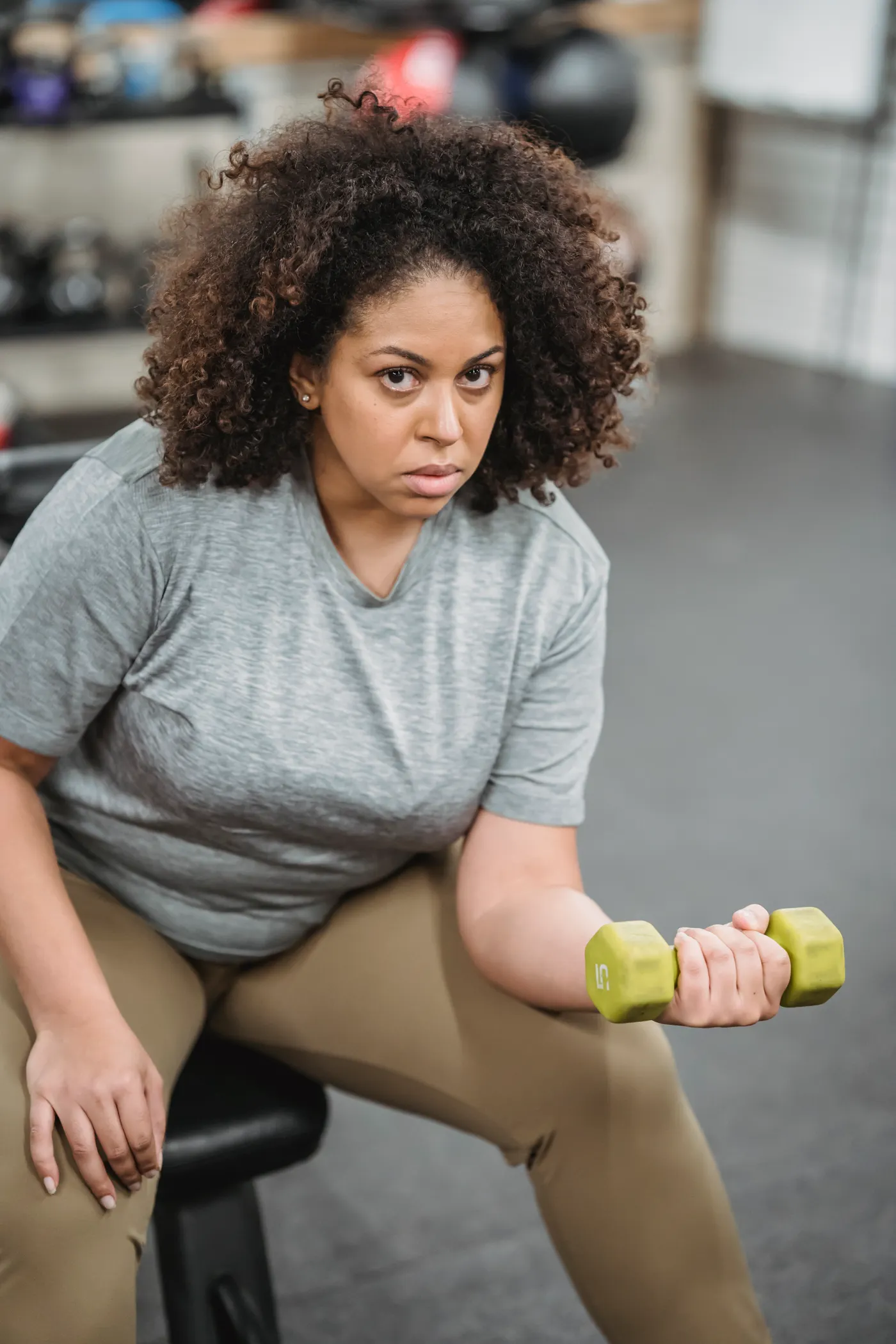 Woman performing a seated dumbbell curl in a gym