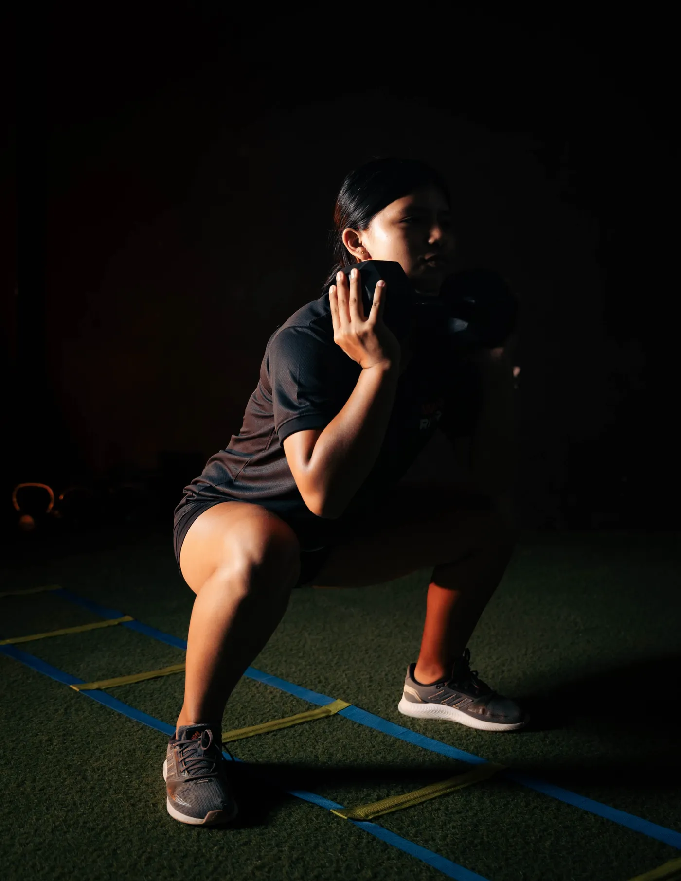 Woman performing a weighted lower-body squat in a gym