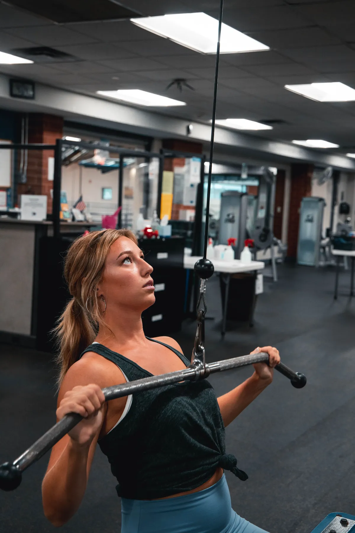 Woman pulling down a cable bar during back training