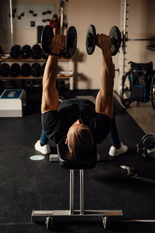 Man using dumbbells on a bench while practicing controlled repetitions