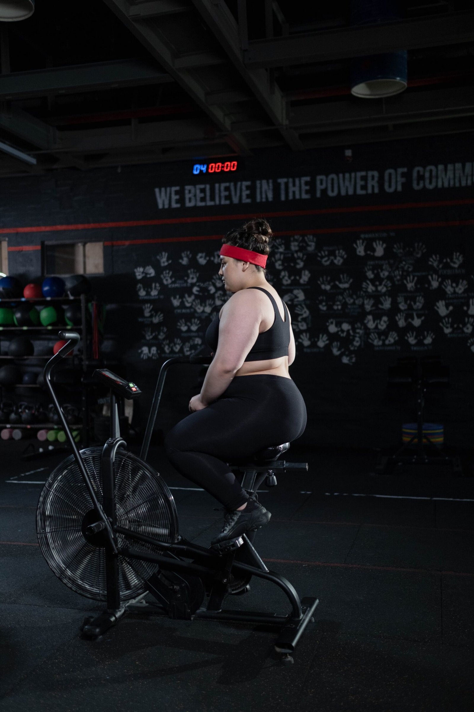 Woman cycling on an air bike in a dark gym