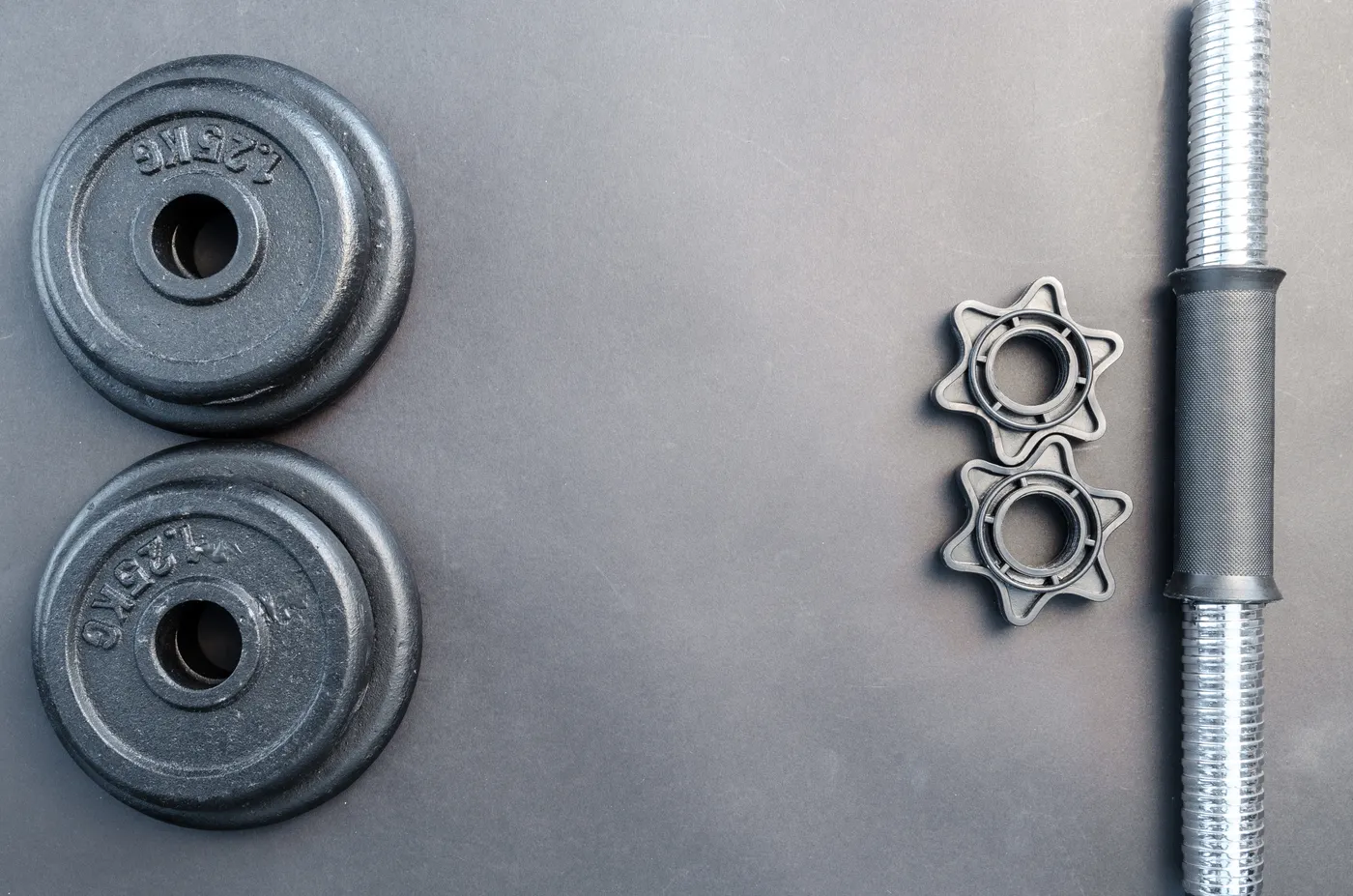 Barbell and dumbbell plates arranged on a gray surface