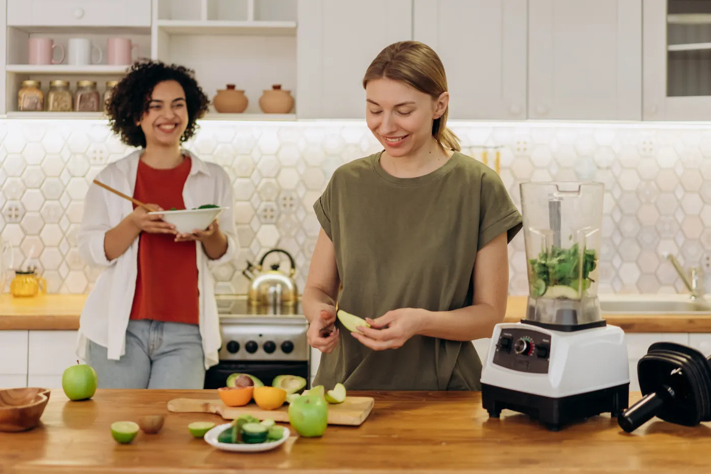 Two women preparing a healthy drink together in a kitchen