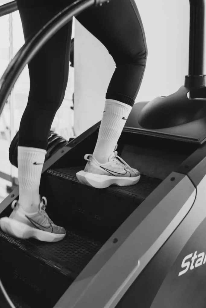 Black-and-white close-up of an athlete using a gym stair climber