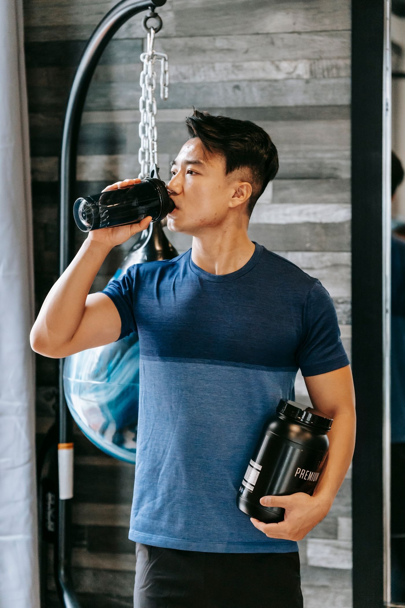 Athlete holding a shaker bottle while drinking in the gym