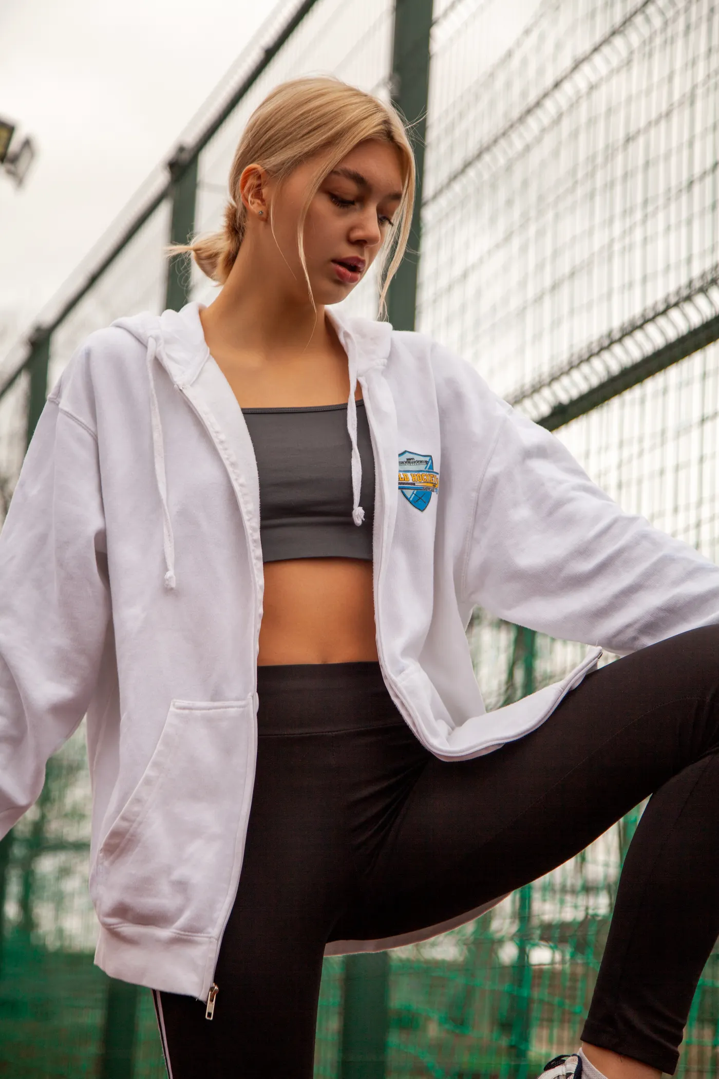 Athlete stretching outdoors in a hoodie and training leggings