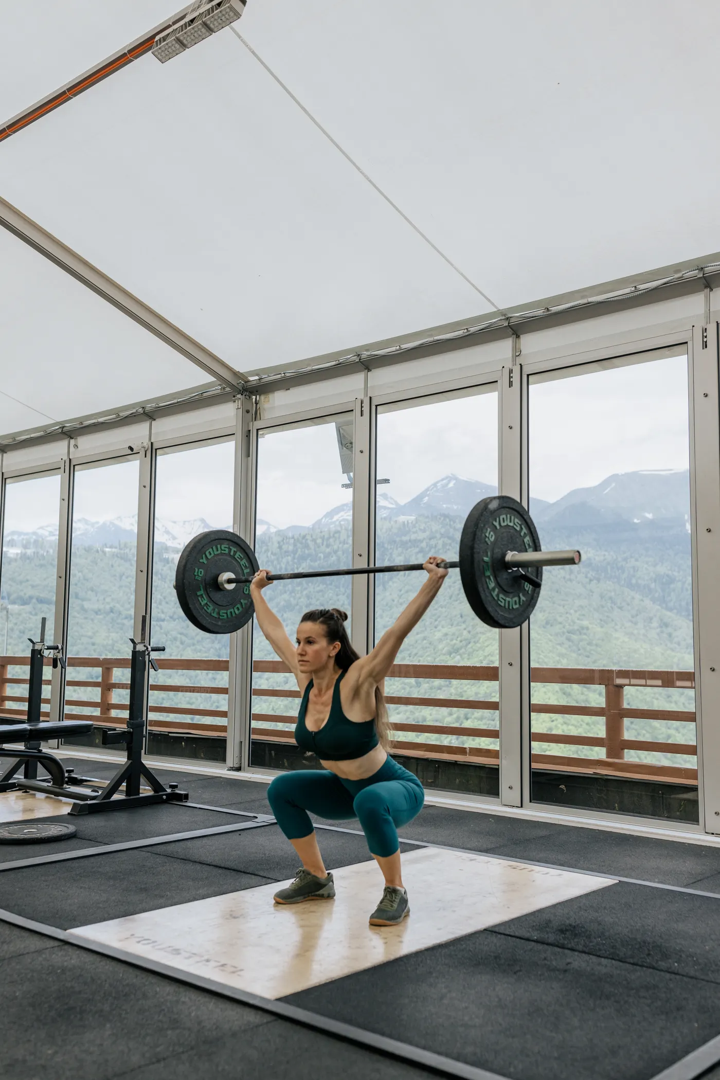 Woman lifting a barbell overhead in a bright gym