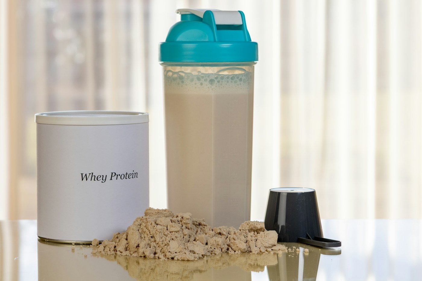 Whey protein powder beside a shaker bottle