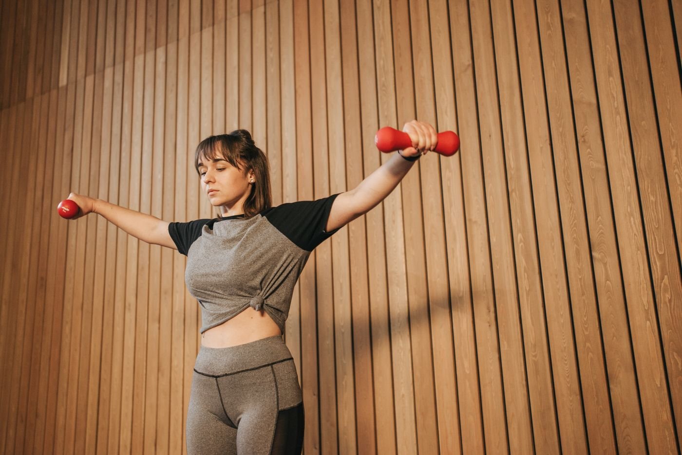 Woman lifting dumbbells with arms raised during strength training