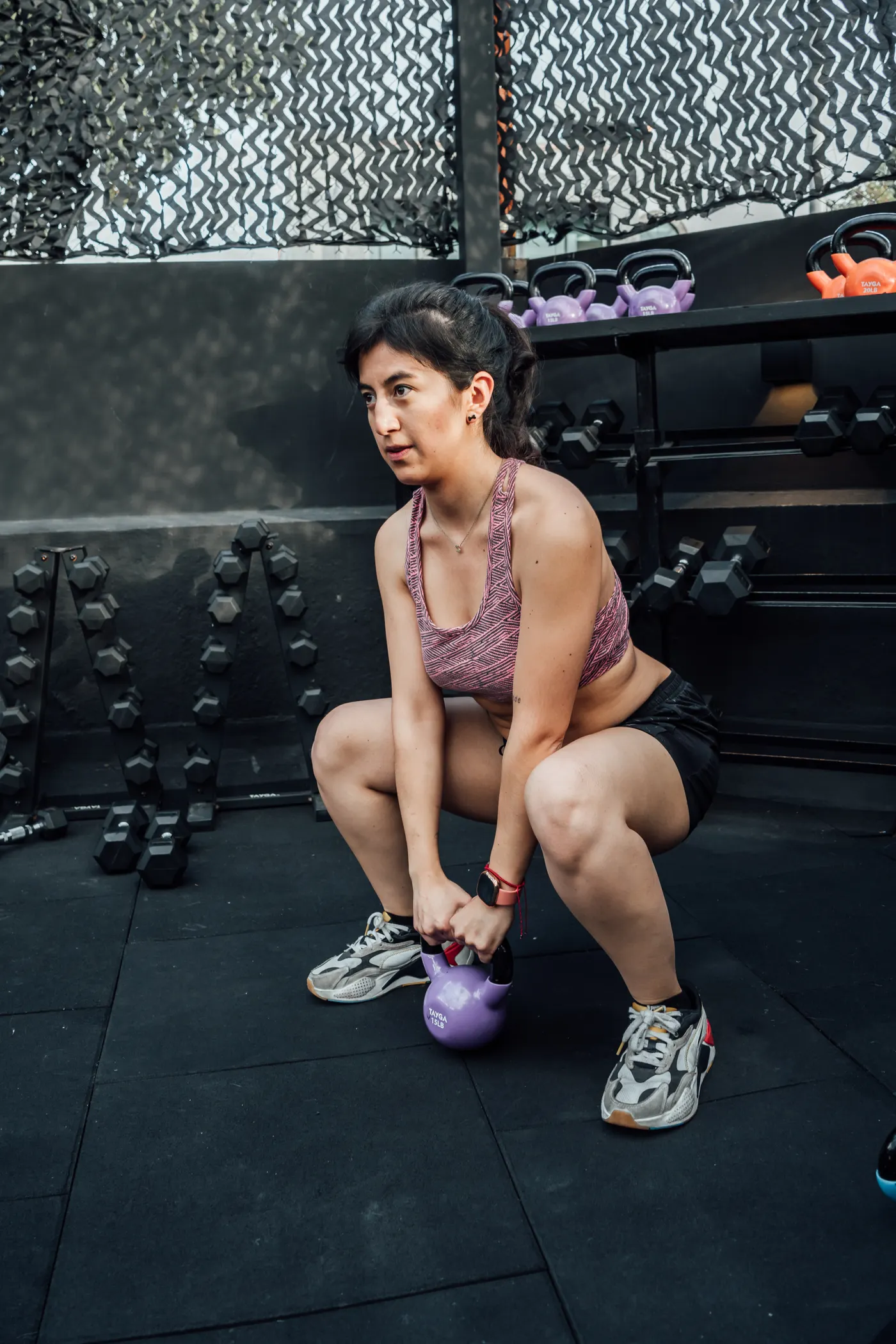 Woman performing a kettlebell squat in a gym