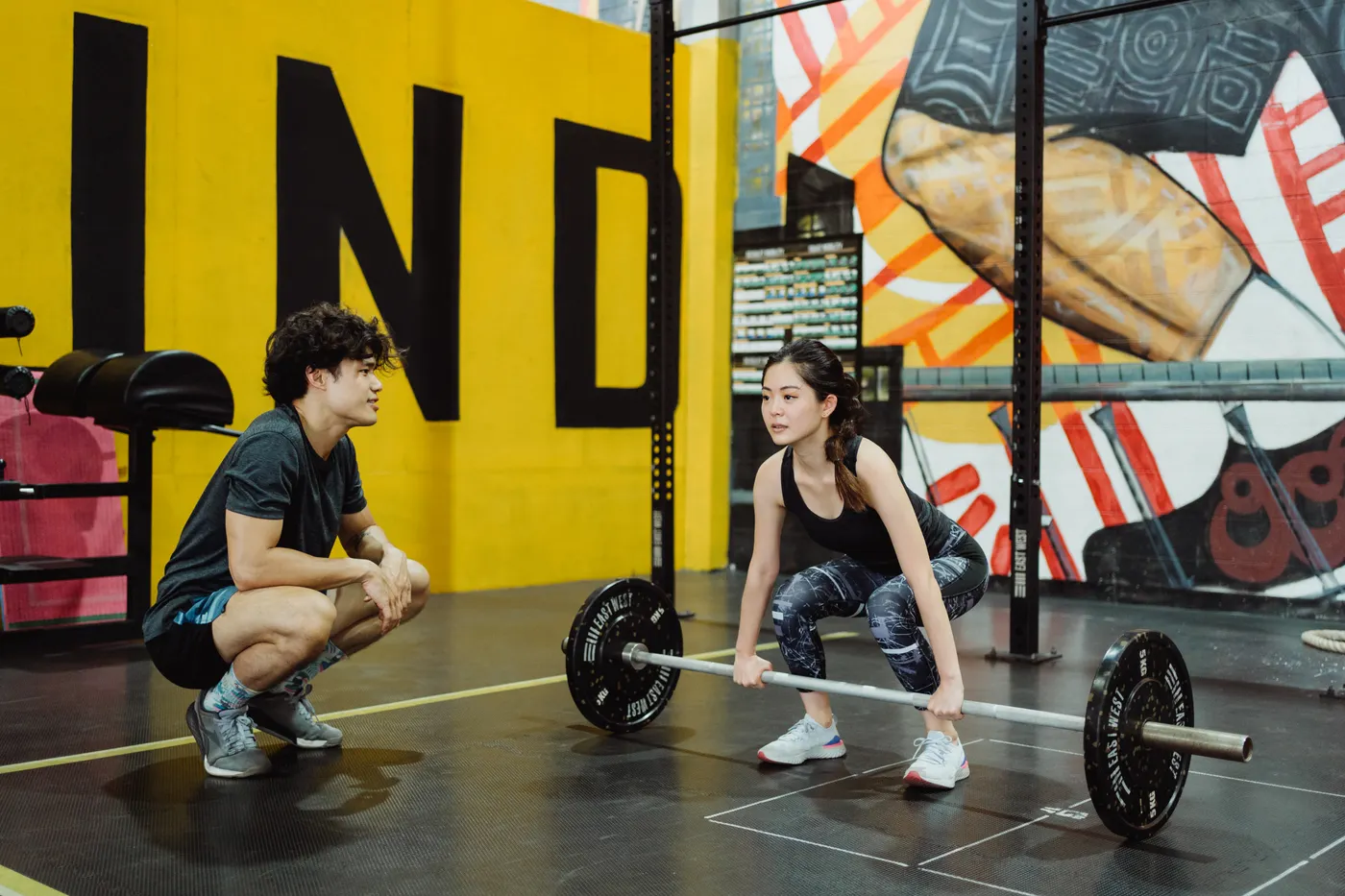 Woman practicing weightlifting with a trainer in a gym