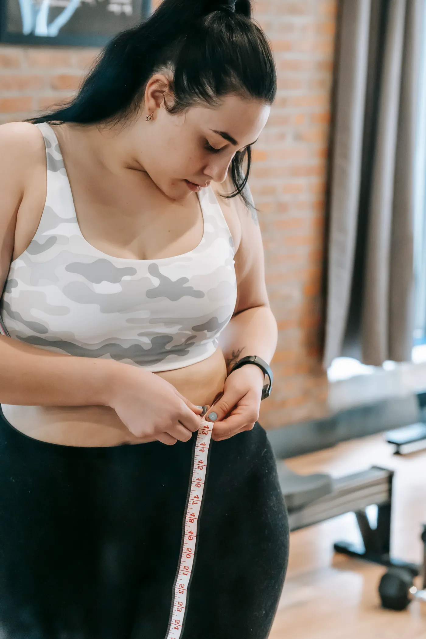 Woman measuring her waist in a gym environment