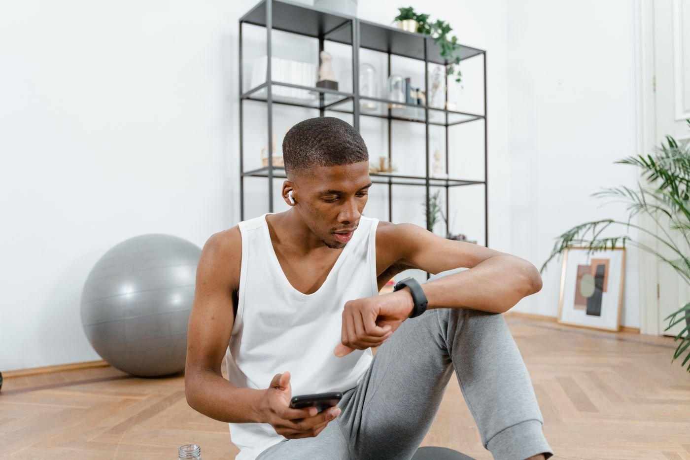 Athlete seated after training while checking a smartwatch and phone
