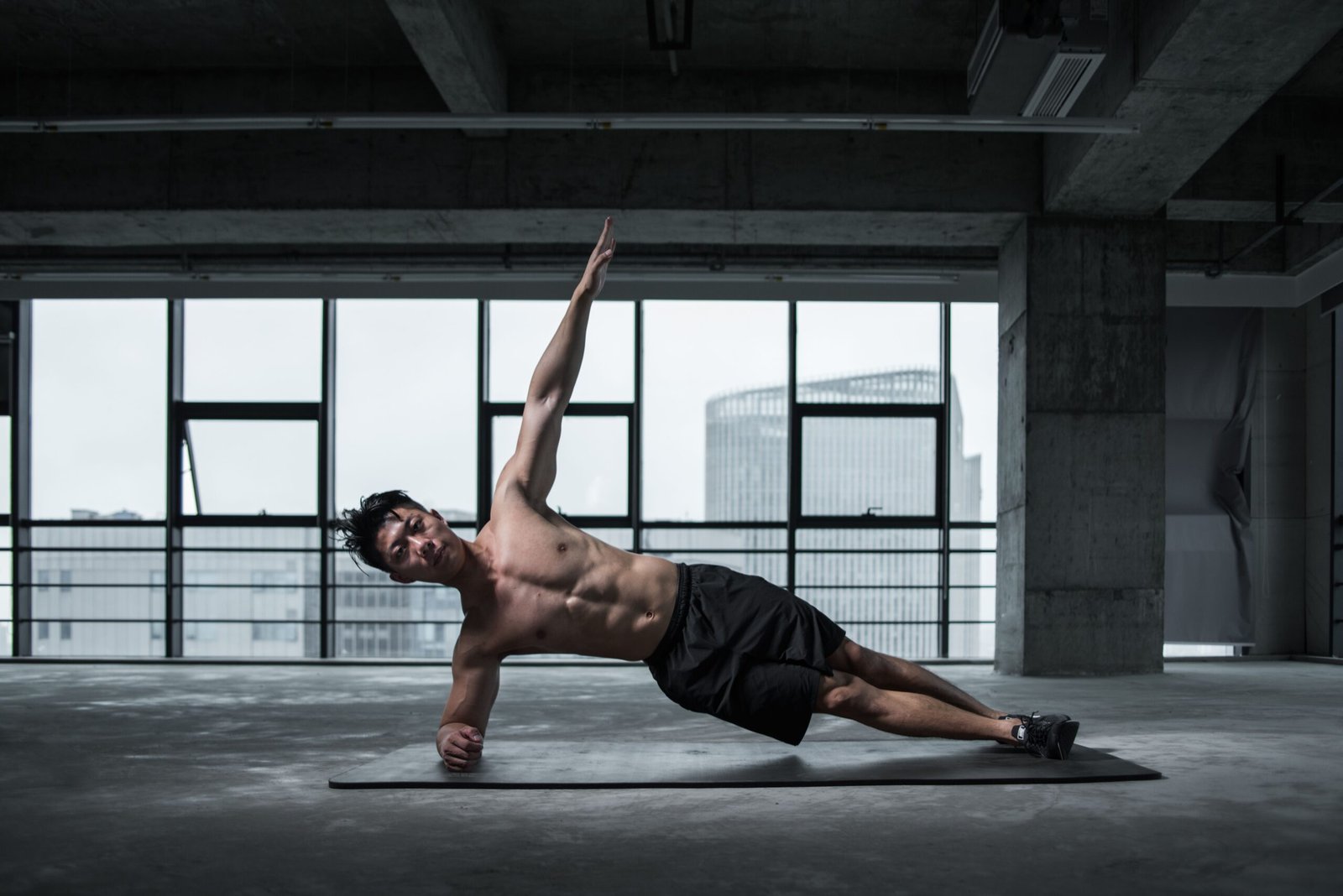 Man holding a side plank in an indoor gym