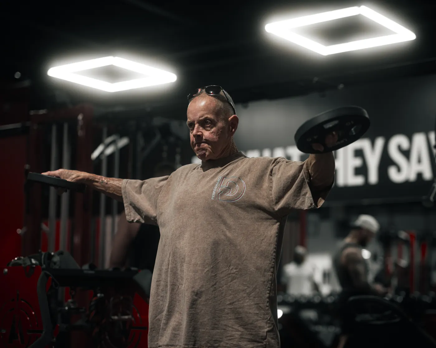 Senior man performing weightlifting exercises inside a gym