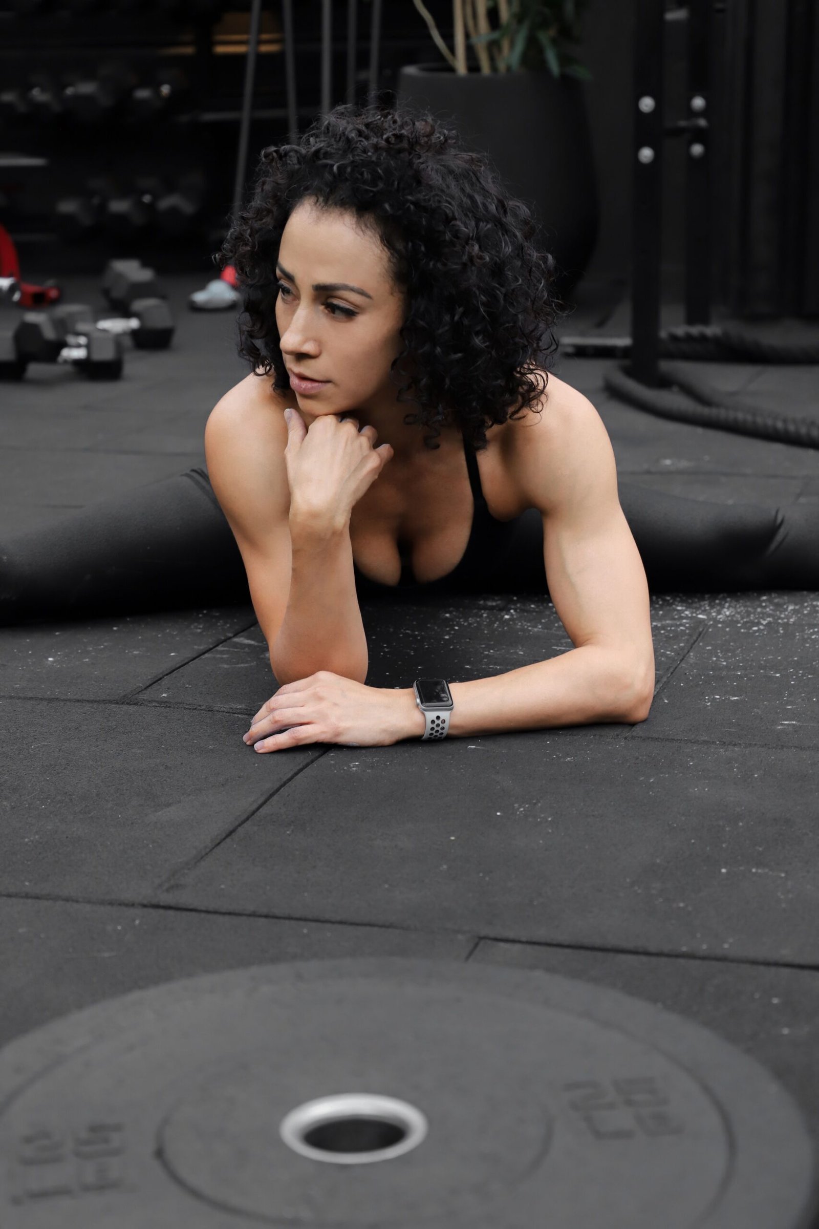 Woman stretching on the floor near weights in a gym