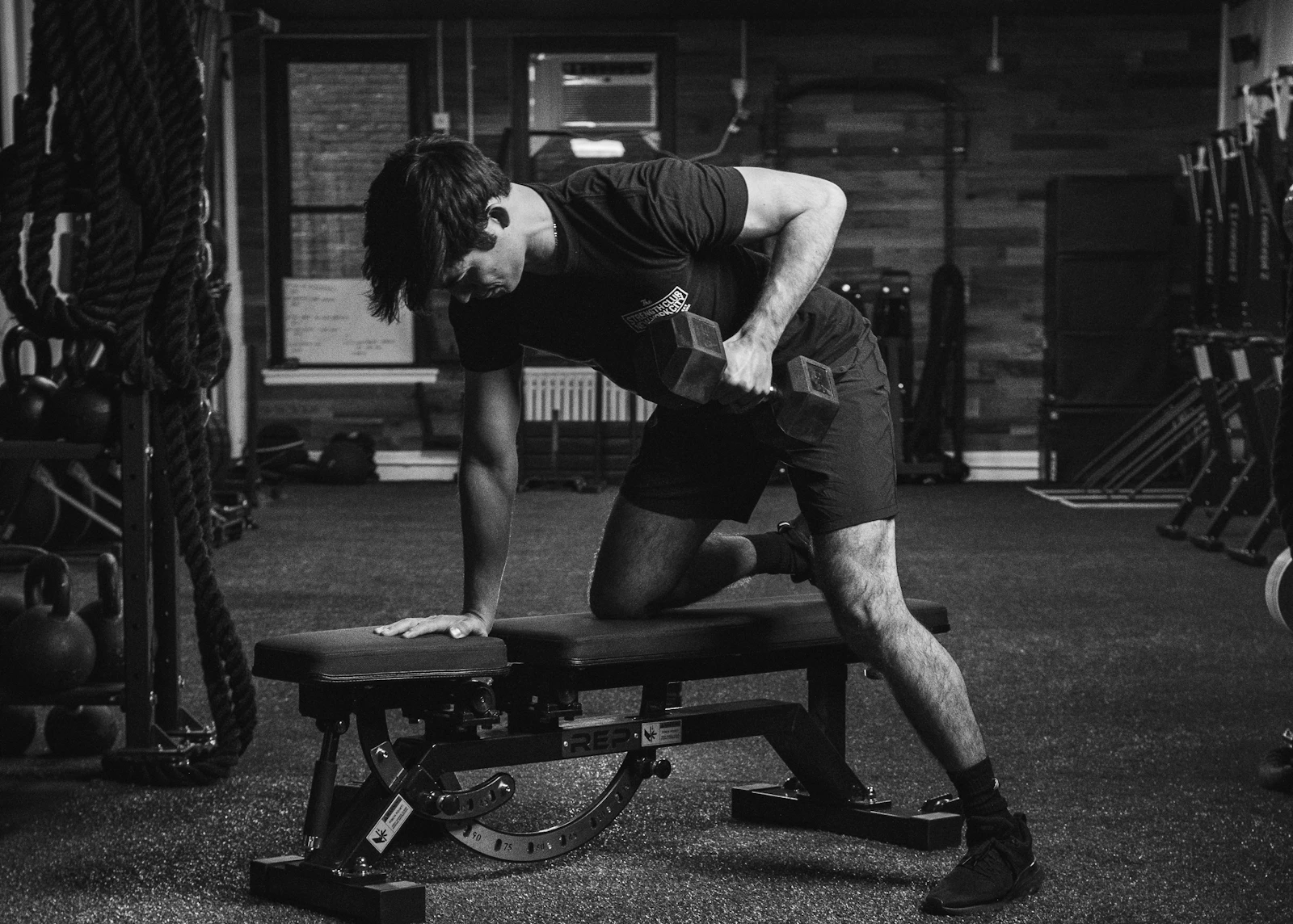 Athlete pressing a dumbbell on a gym bench