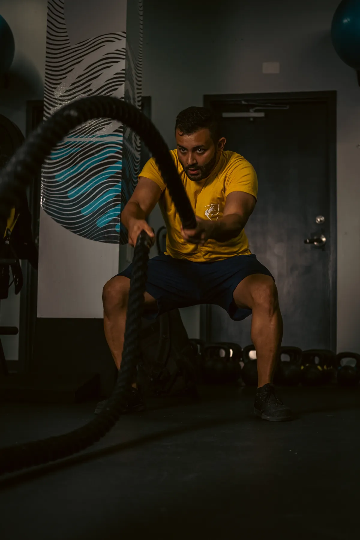 Man performing an intense battle-rope exercise in a gym