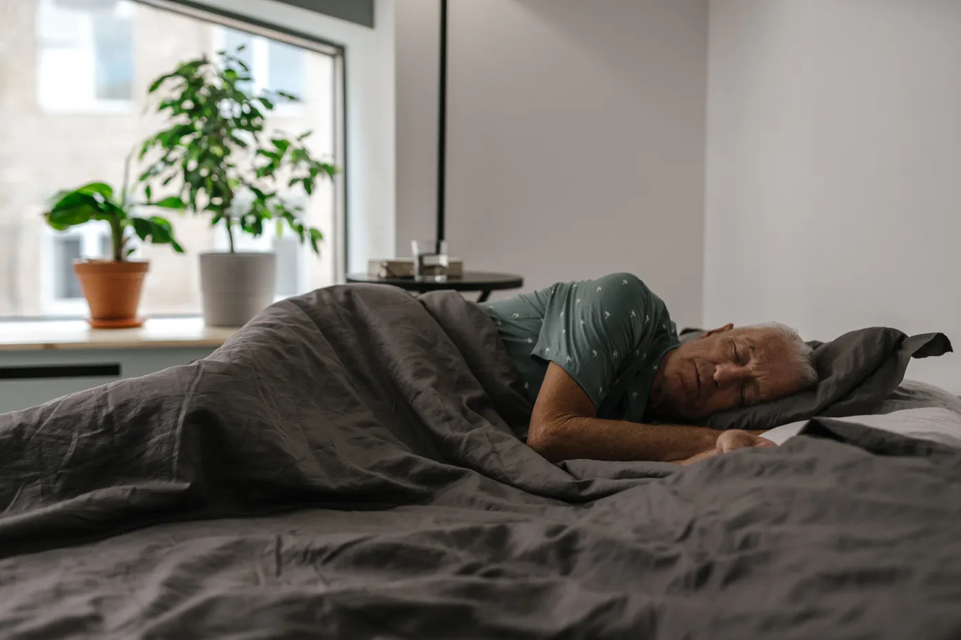 Older man resting in bed in a naturally lit bedroom