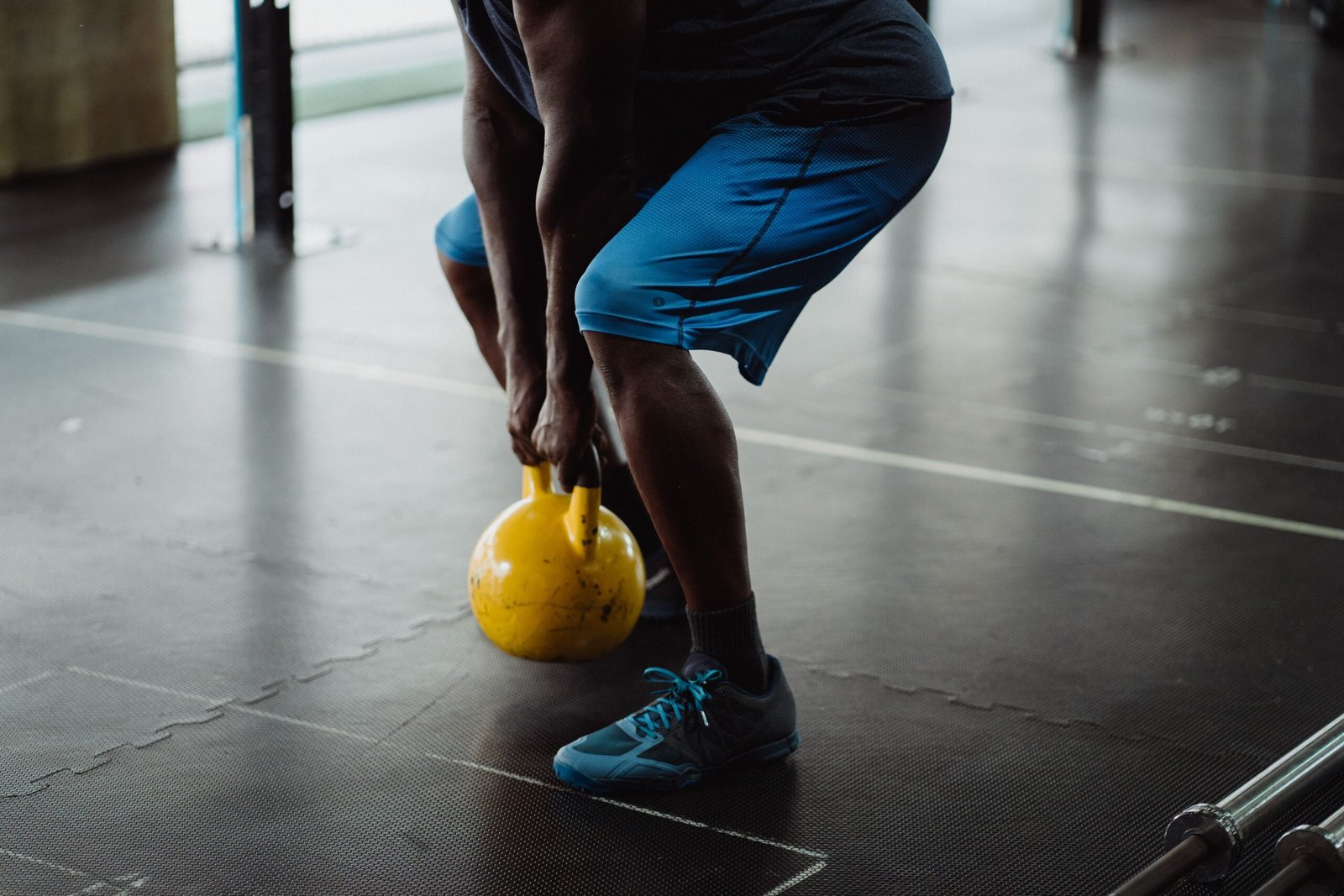 Athlete gripping a yellow kettlebell during a lower-body strength exercise