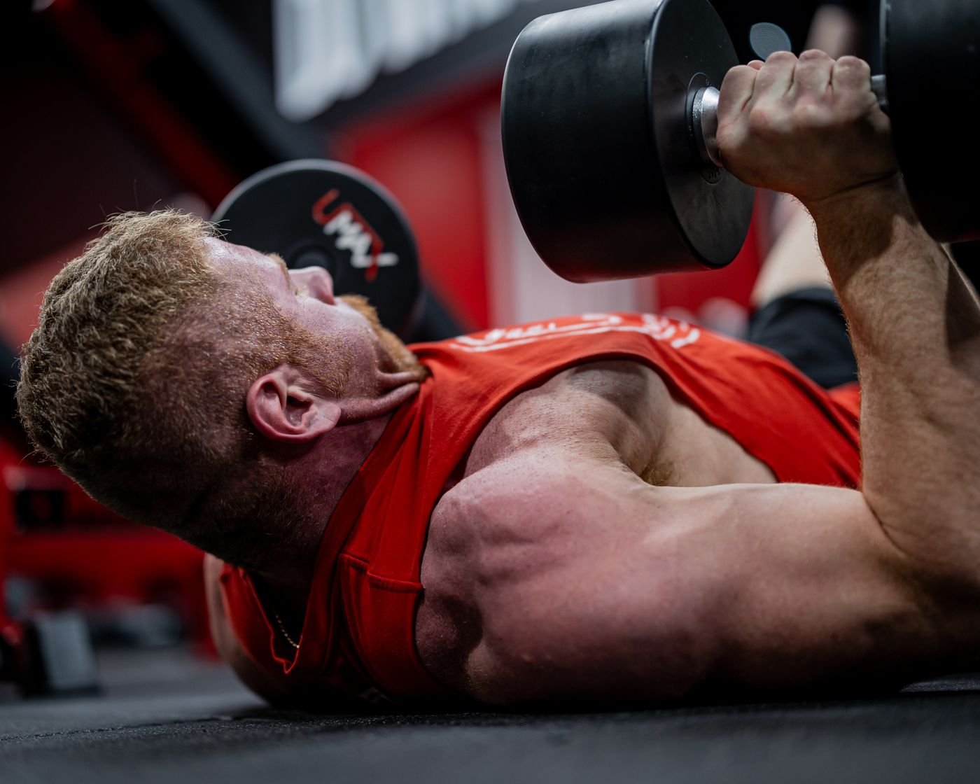 Man pressing dumbbells while lying on a gym floor
