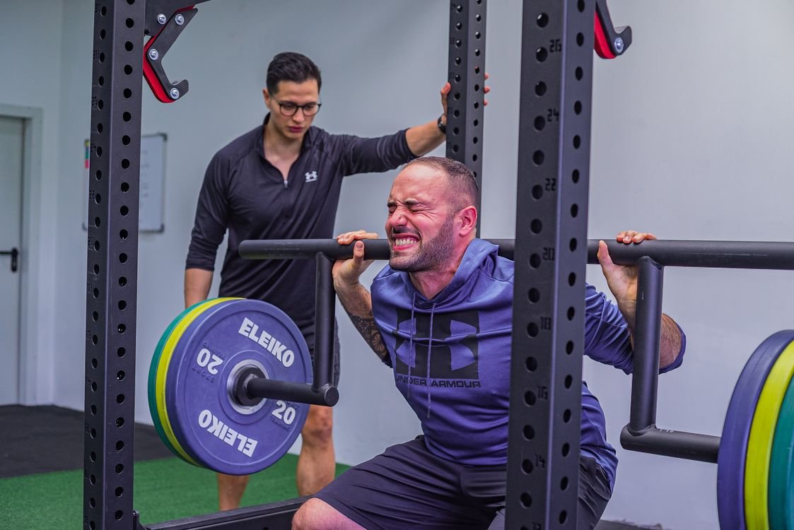 Athlete performing a coached barbell squat in a gym